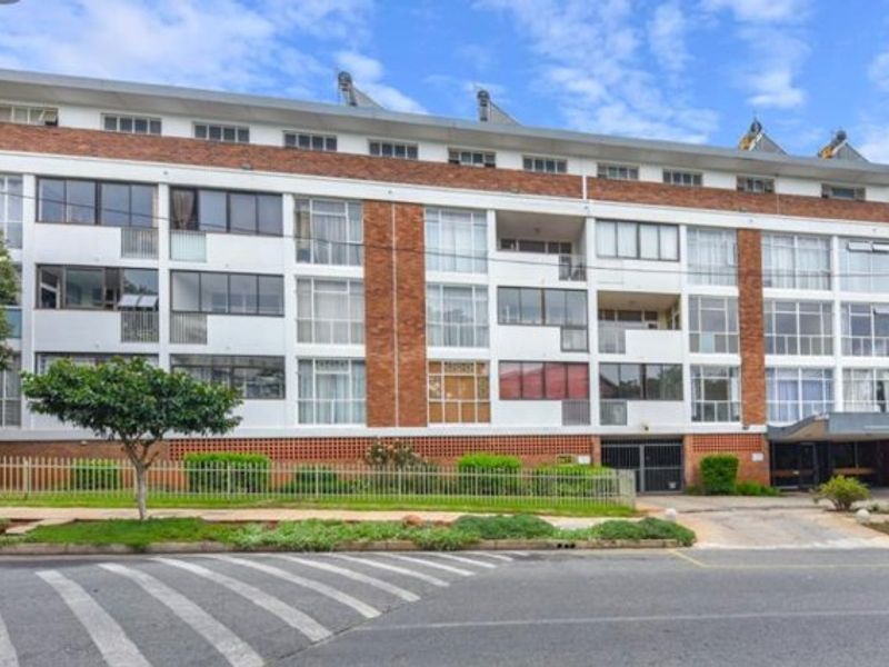 Front elevation of a multi-story apartment building featuring brick facade, balconies, and solar water heating systems.