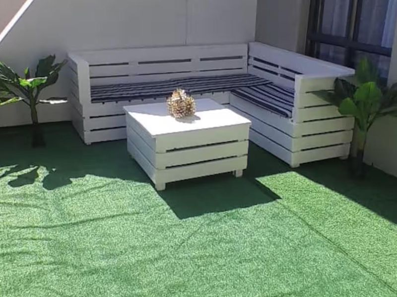 A private balcony area featuring artificial grass flooring and access via a sliding glass door.