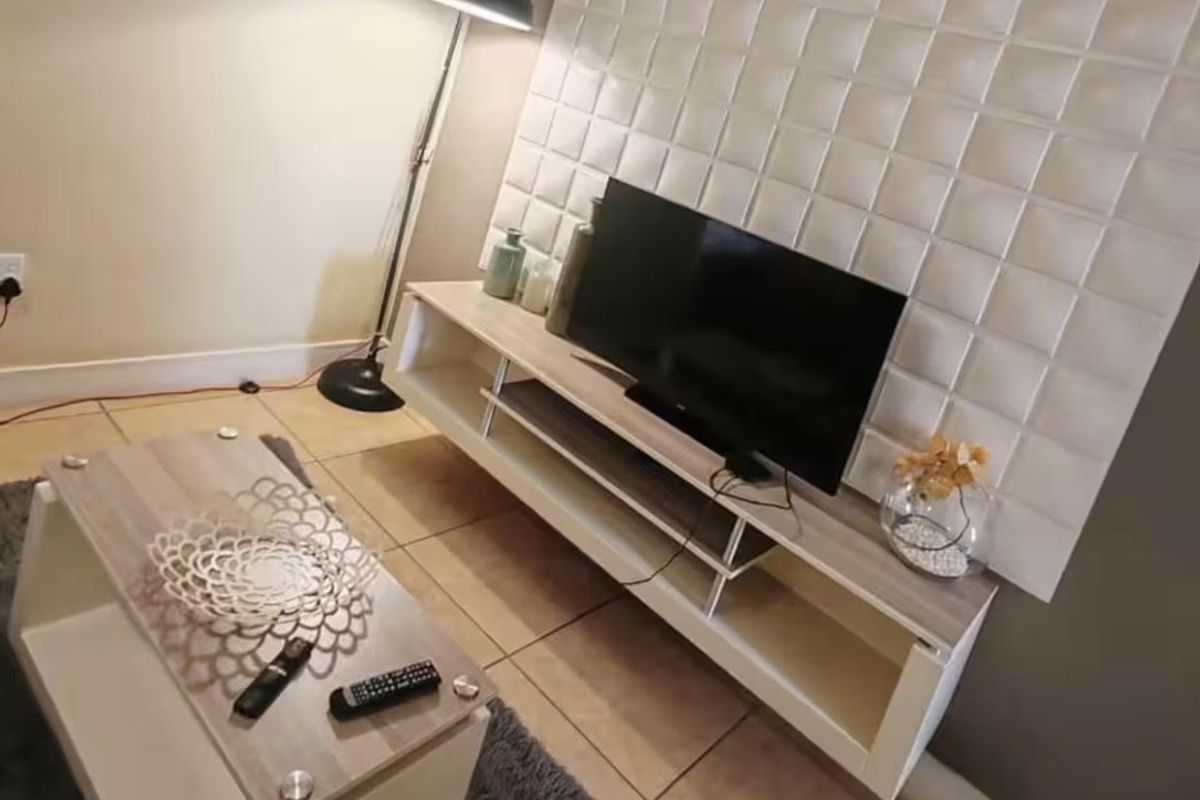 A living room area featuring a decorative textured wall panel and tiled flooring.