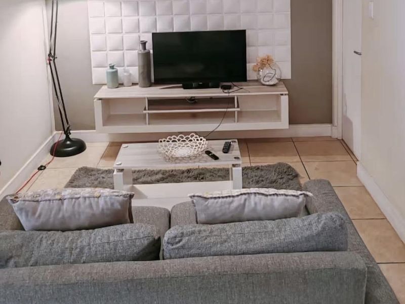 A cozy living room featuring tiled flooring, a wall-mounted media console, and a decorative textured feature wall.