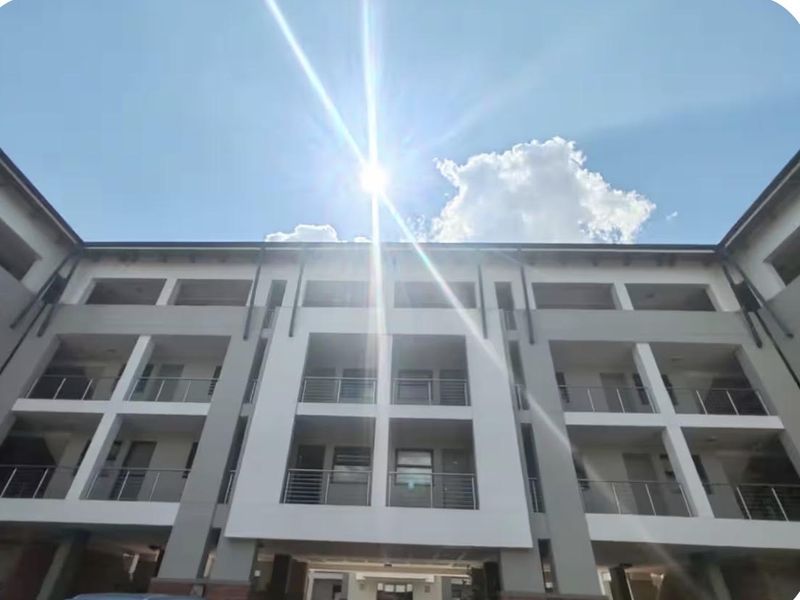 A low-angle view of a modern multi-story apartment building facade featuring private balconies with metal railings.