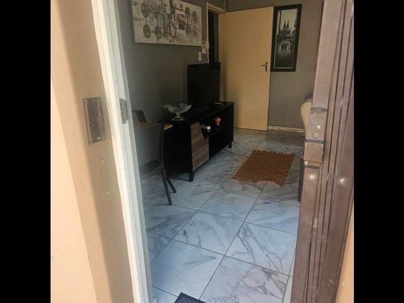 A view into a living area featuring light-colored marble-effect floor tiles and a standard internal door.