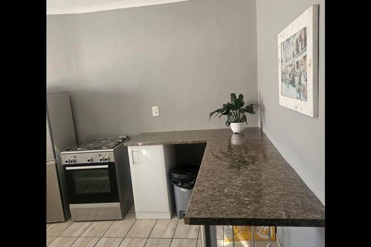 A functional kitchen area featuring granite countertops, tiled flooring, and a freestanding oven, providing a practical workspace for cooking and meal preparation.