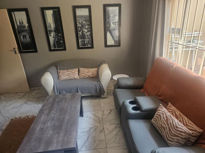 A living room featuring tiled flooring and security bars on the windows, providing a functional and secure living space.