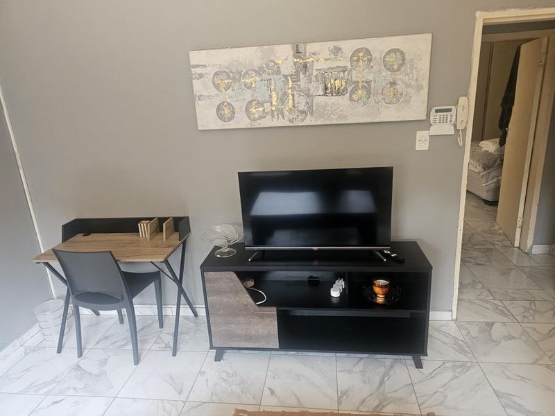 A living area featuring marble-look tiled flooring, a wall-mounted security alarm keypad, and an intercom system.