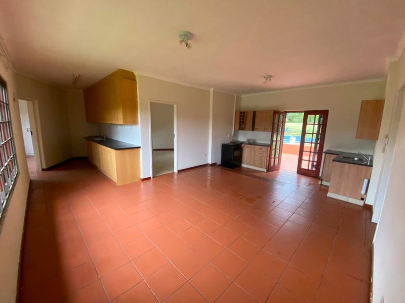 Spacious open-plan kitchen and living area featuring tiled flooring, built-in cabinetry, and direct access to the outdoor patio and pool area.