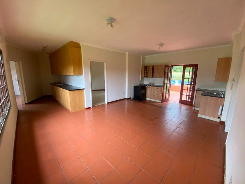 Spacious open-plan kitchen area featuring terracotta floor tiles, built-in cabinetry, and direct access to the outdoor patio and pool area.