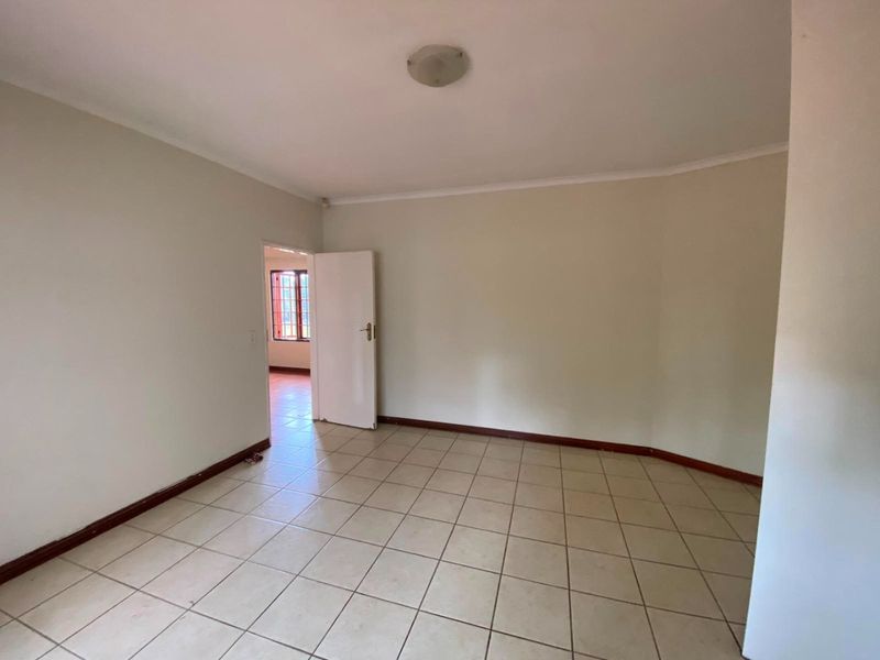 A bright, empty living area featuring neutral tiled flooring and clean walls, providing a versatile blank canvas for interior design.