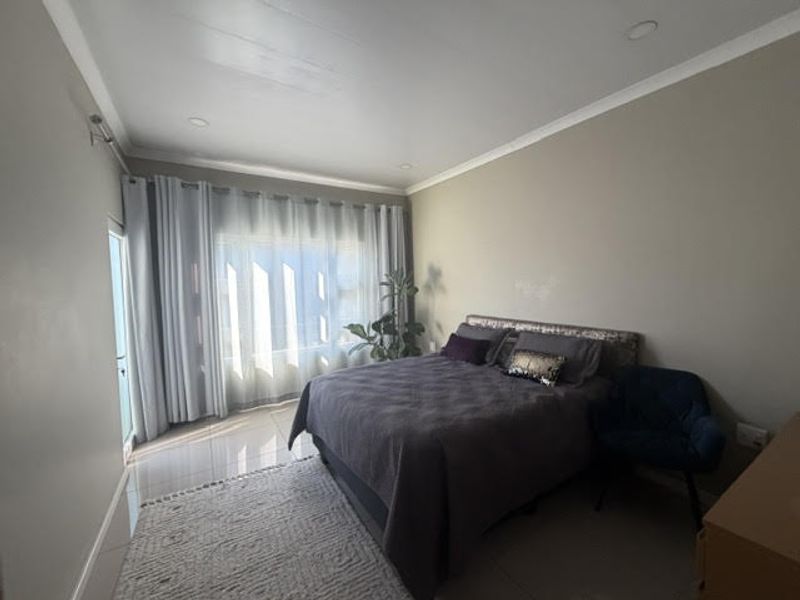 A well-lit bedroom featuring neutral walls, tiled flooring, and a sliding door leading to an outdoor area.