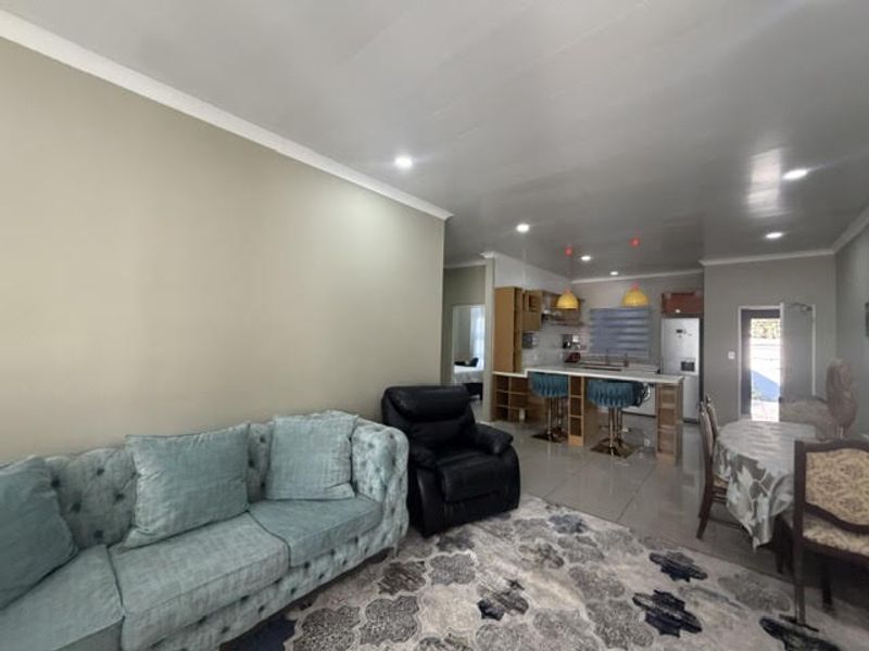An open-plan living and kitchen area featuring tiled flooring, recessed lighting, and a functional kitchen island with built-in cabinetry.