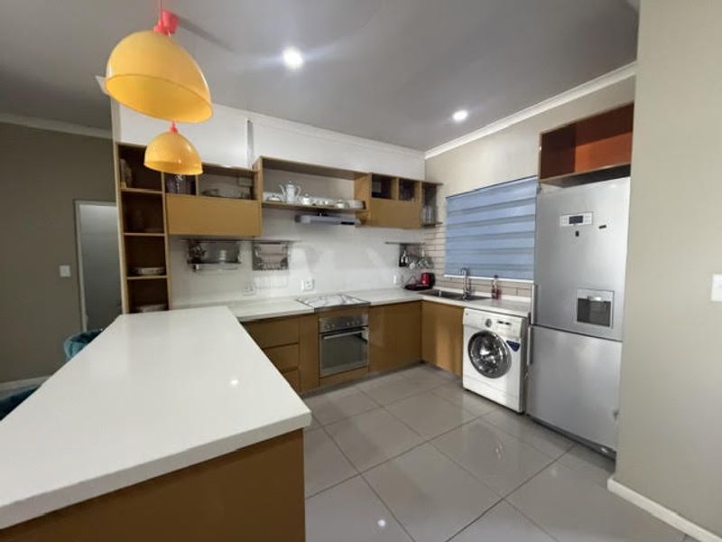 Modern kitchen featuring built-in cabinetry, quartz countertops, stainless steel appliances, and a functional island, providing a clean and efficient workspace.