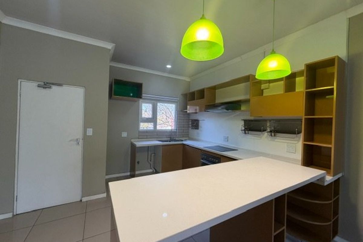 Modern kitchen featuring built-in cabinetry, a central island, integrated hob and oven, and tiled flooring in an open-plan layout.