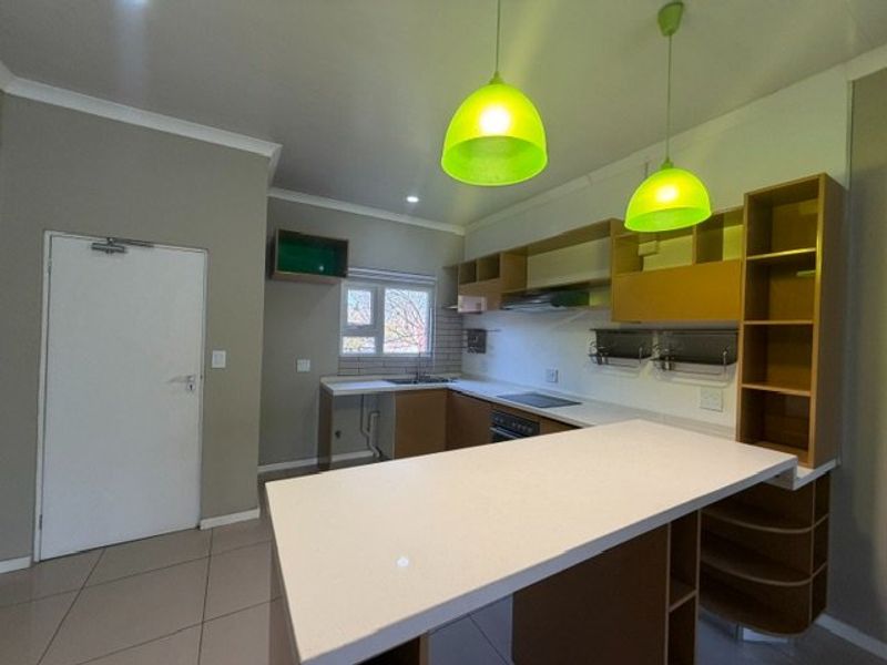 Modern kitchen featuring built-in cabinetry, a central island, integrated hob and oven, and tiled flooring in an open-plan layout.