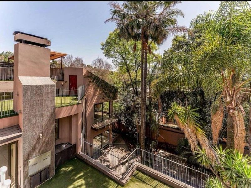 Multi-level rear exterior featuring tiered terraces, metal balustrades, a built-in braai, and a lush landscaped garden with mature trees.