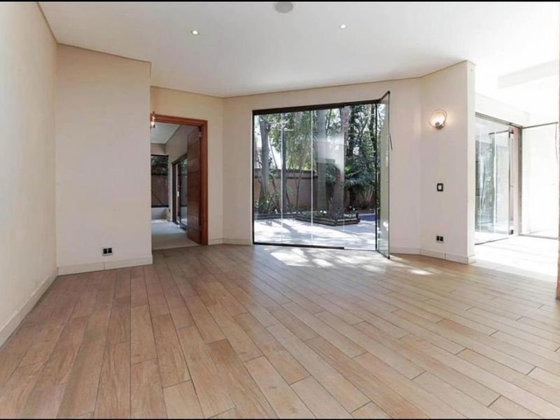 Spacious, light-filled living area featuring modern timber-look tile flooring, a striking stone feature wall, and large glass doors opening to the garden.