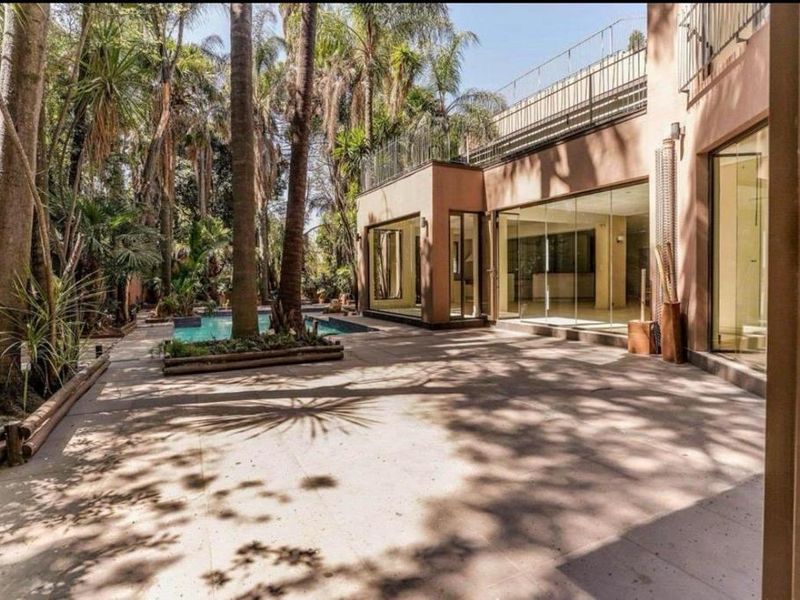Rear exterior view featuring a paved patio area, swimming pool, and large glass sliding doors leading into the home.