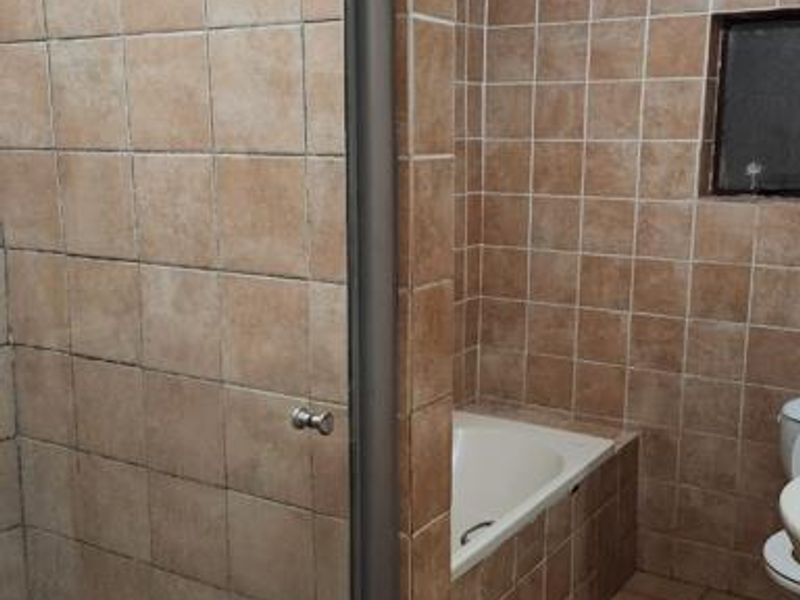 A dated bathroom featuring a built-in bathtub, a separate shower enclosure, and full-height ceramic wall tiling.