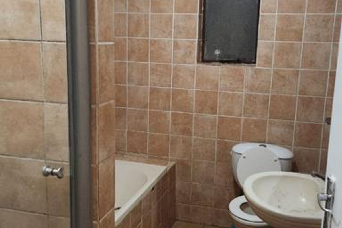 A dated bathroom featuring a bathtub, pedestal sink, toilet, and shower enclosure with full-height wall tiling and floor tiles.