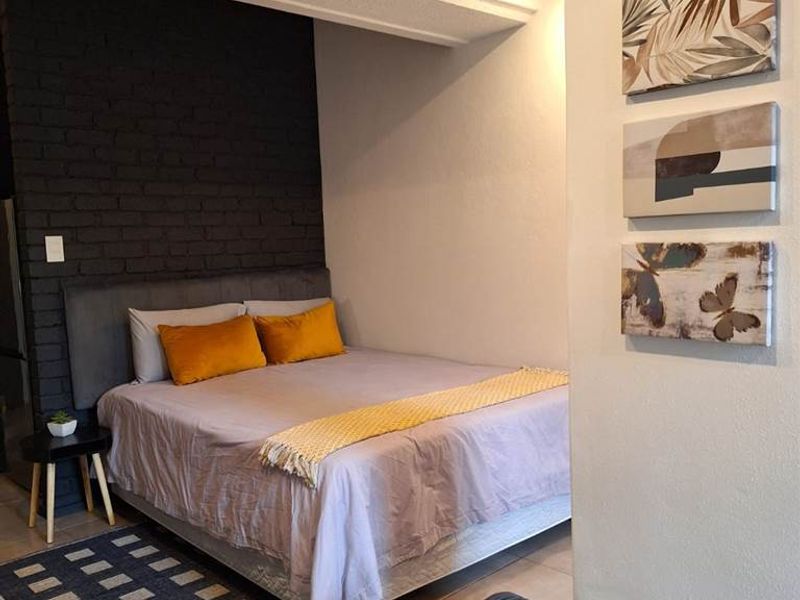 A bedroom featuring an exposed black brick feature wall and a recessed ceiling design, providing a modern aesthetic.