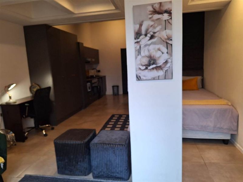 Open-plan apartment layout featuring tiled flooring, built-in cabinetry, and a recessed ceiling design, creating a functional living and sleeping space.