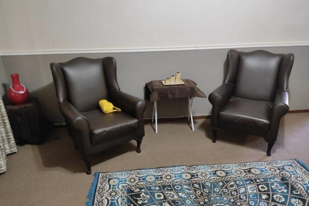 A living room area featuring neutral wall paint with a decorative chair rail and carpeted flooring.