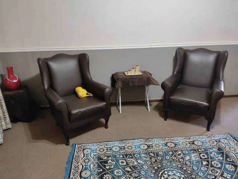 A living room area featuring neutral wall paint with a decorative chair rail and carpeted flooring.