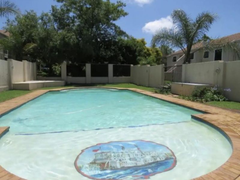 A private swimming pool area featuring brick paving, surrounding boundary walls, and established garden landscaping.