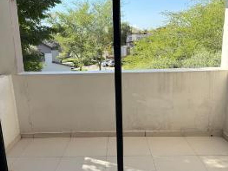 A covered balcony featuring tiled flooring, a pergola structure, and a sliding glass door entrance with views of the surrounding neighborhood.