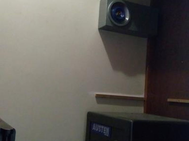 A small utility or storage space featuring built-in shelving and a wall-mounted speaker.
