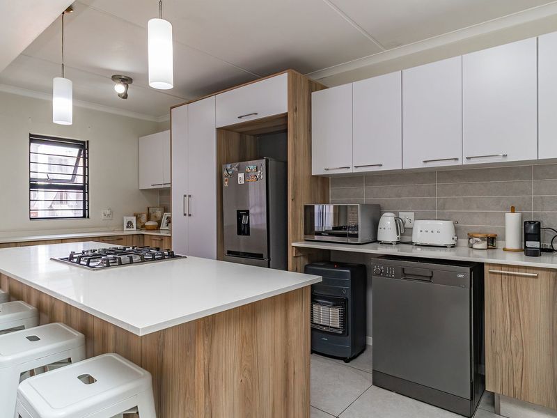 Modern kitchen featuring a central island with a gas hob, ample built-in cabinetry, stone countertops, and a tiled backsplash.