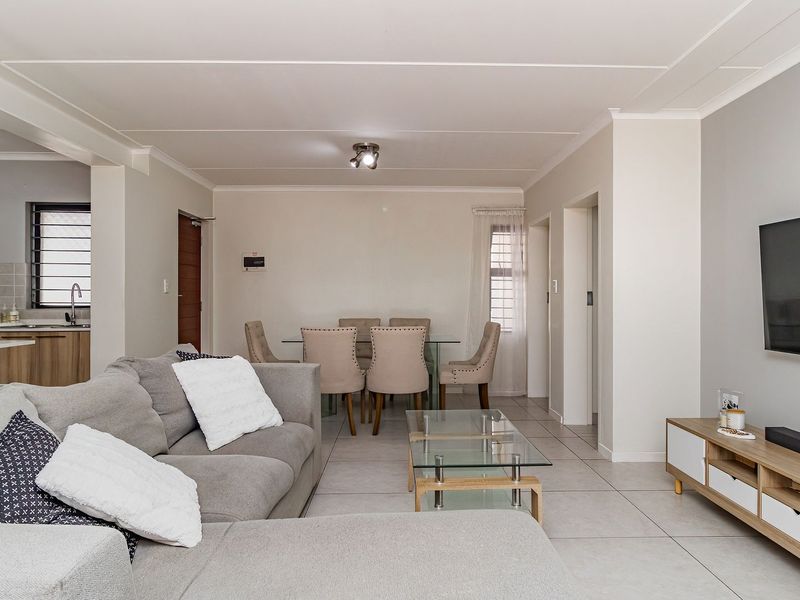 Spacious open-plan living and dining area featuring neutral tiled flooring, modern kitchen cabinetry, and a seamless flow between the kitchen, dining, and lounge spaces.