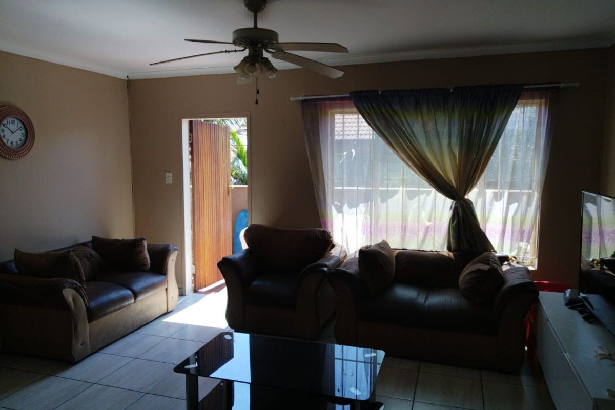 A living room featuring tiled flooring, a ceiling fan, and direct access to an outdoor area through a sliding door.