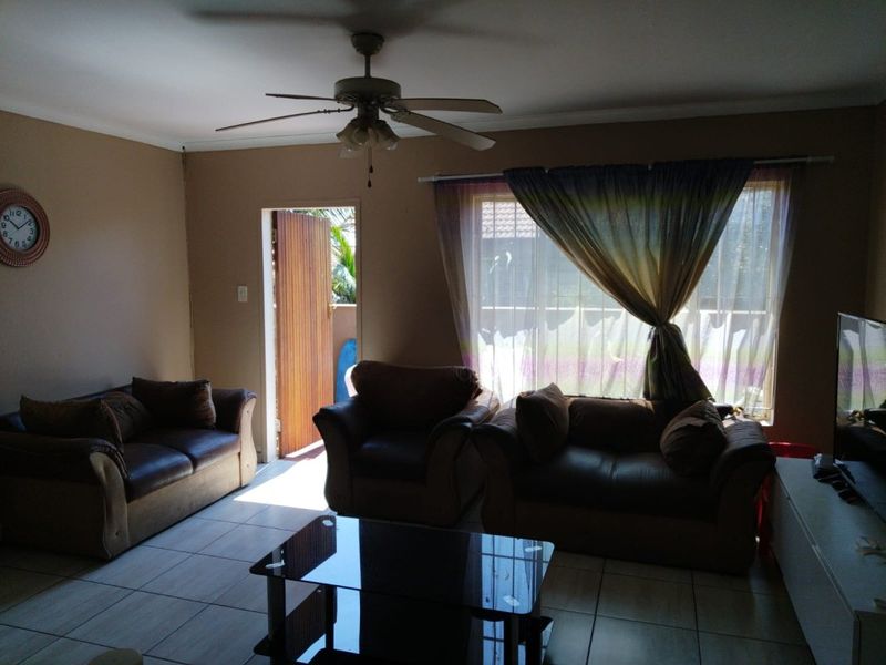 A living room featuring tiled flooring, a ceiling fan, and direct access to an outdoor area through a sliding door.