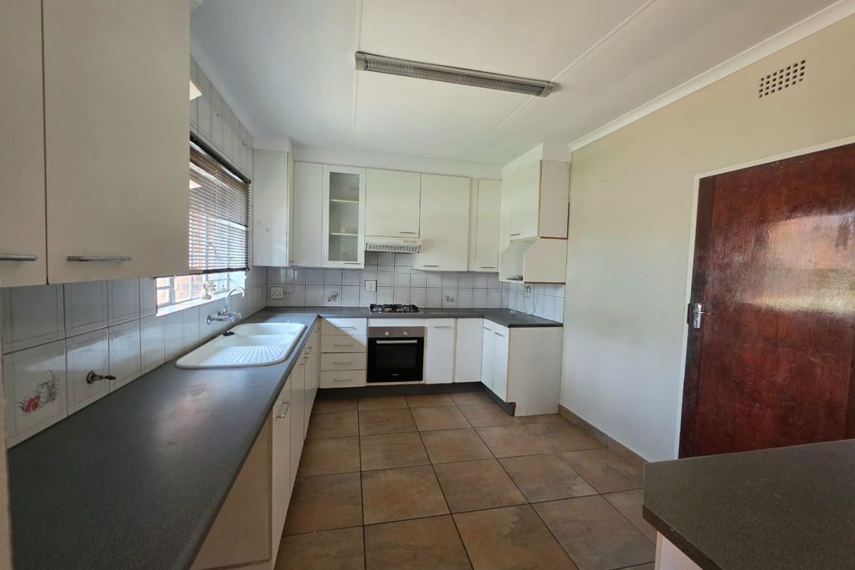 A functional kitchen featuring built-in cabinetry, a gas hob, an integrated oven, and tiled flooring, offering a clean space ready for modernization.