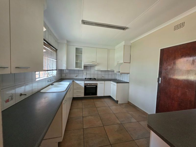 A functional kitchen featuring built-in cabinetry, a gas hob, an integrated oven, and tiled flooring, offering a clean space ready for modernization.