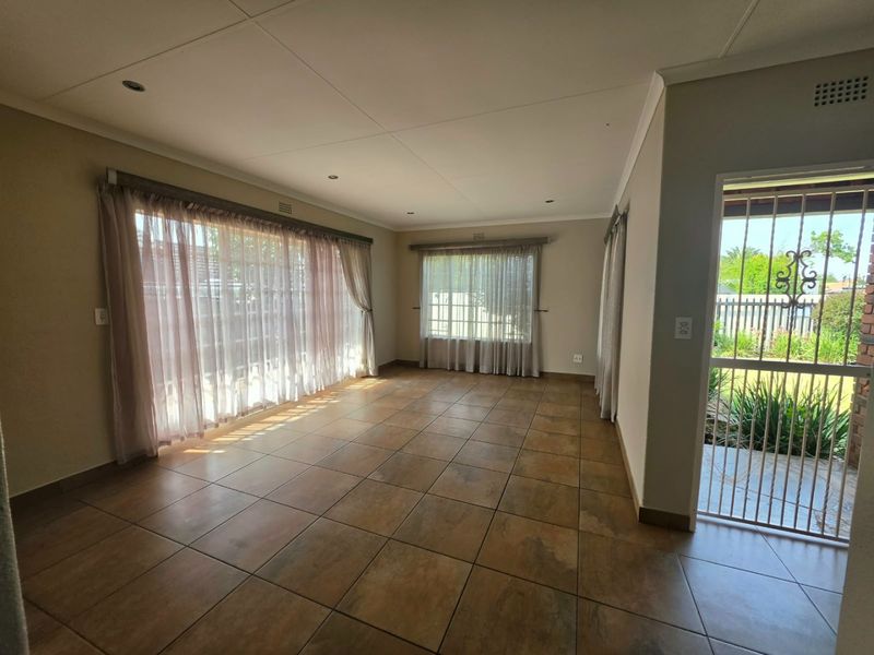 Spacious, light-filled living area featuring neutral tiled flooring, recessed lighting, and large sliding glass doors providing direct access to the garden.