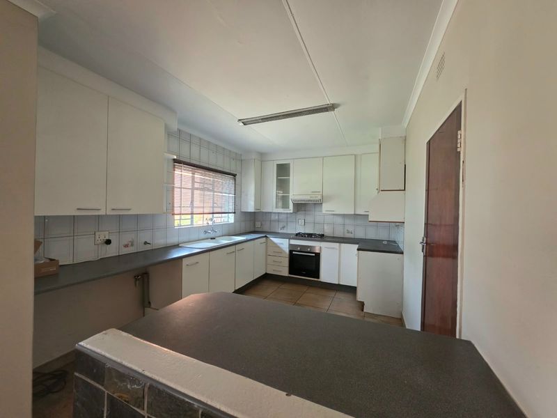 A functional kitchen featuring white built-in cabinetry, dark laminate countertops, a built-in oven with gas hob, and tiled flooring.