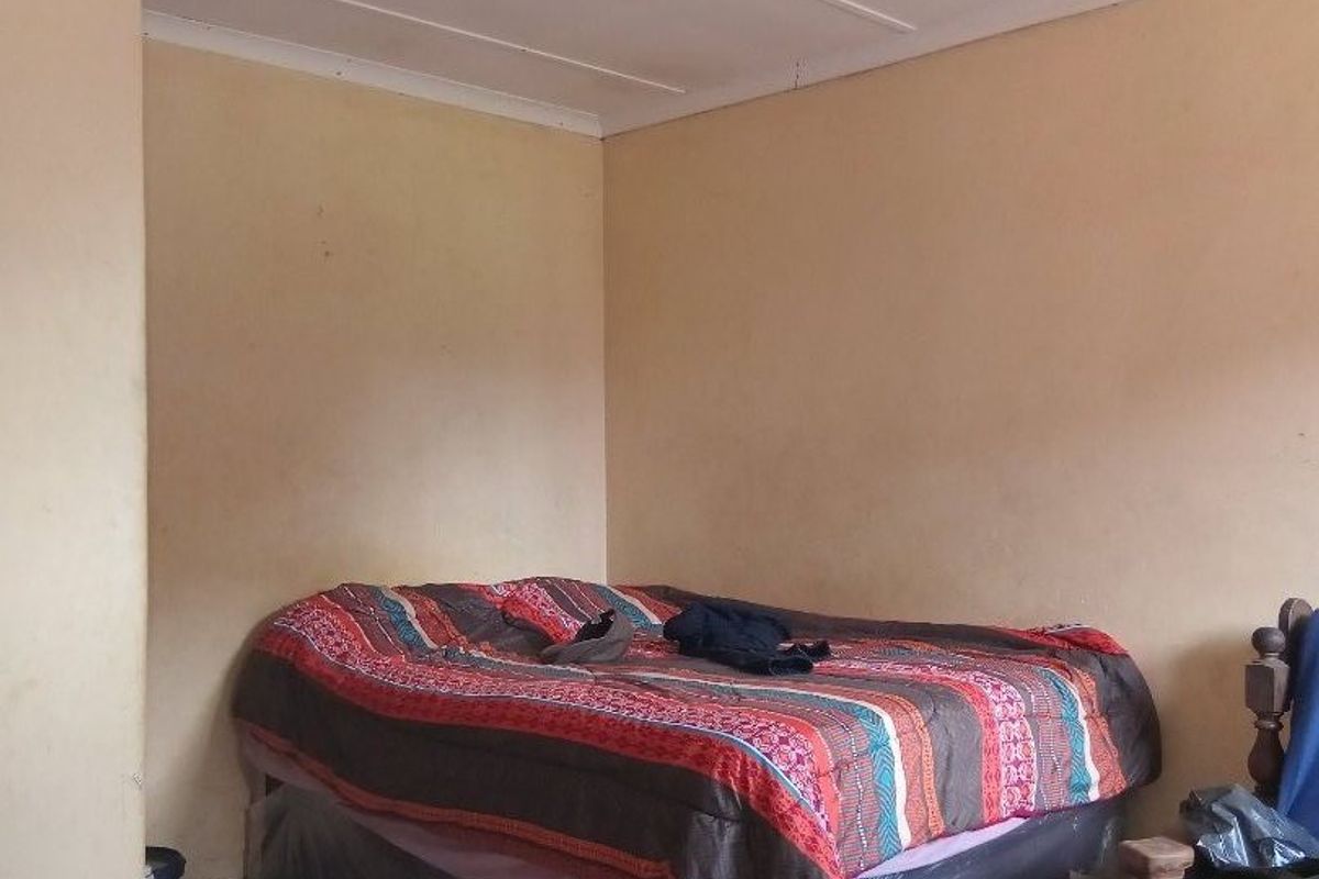 A simple bedroom featuring tiled flooring and neutral wall finishes, offering a functional space ready for cosmetic updates.