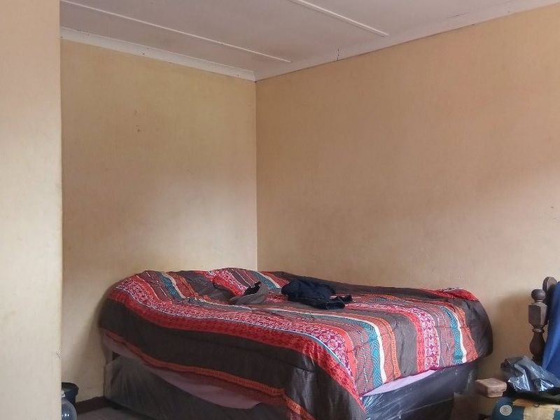 A simple bedroom featuring tiled flooring and neutral wall finishes, offering a functional space ready for cosmetic updates.