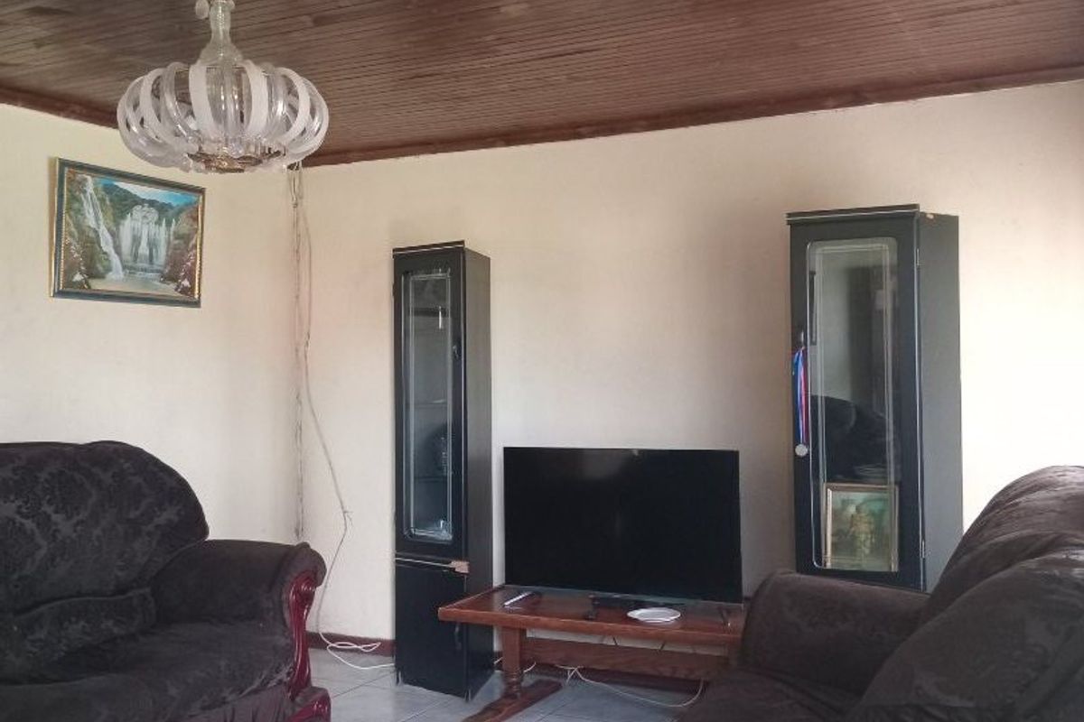 A living room featuring tiled flooring and a timber tongue and groove ceiling, requiring minor maintenance to the lighting fixture wiring.