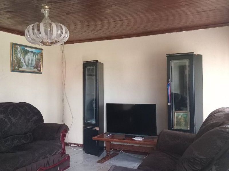A living room featuring tiled flooring and a timber tongue and groove ceiling, requiring minor maintenance to the lighting fixture wiring.