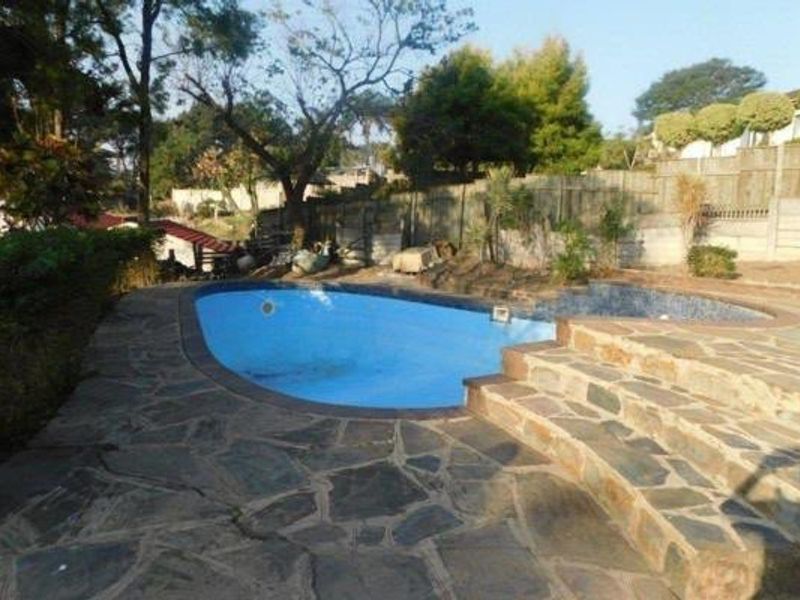 Outdoor pool area featuring a swimming pool with stone paved surround and retaining walls, set within a garden environment.