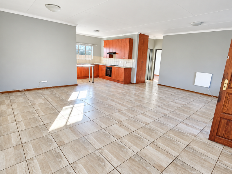 Spacious open-plan living area featuring tiled flooring and a functional kitchen with built-in cabinetry, oven, and extractor fan.