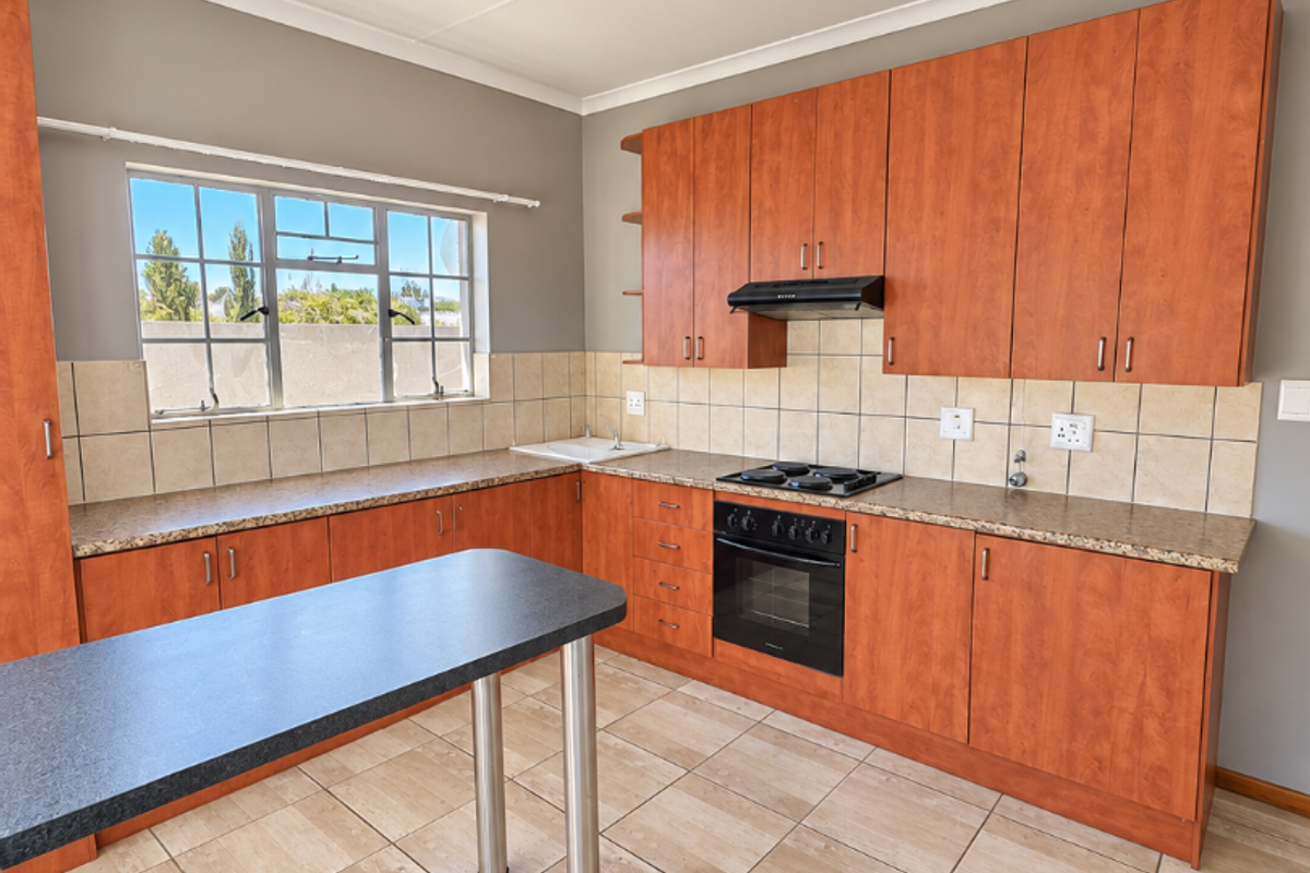 A functional kitchen featuring wood-finish cabinetry, granite-look laminate countertops, a built-in oven with hob, and a breakfast bar island.