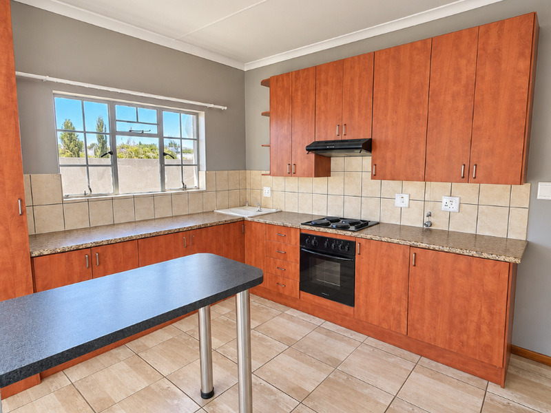 A functional kitchen featuring wood-finish cabinetry, granite-look laminate countertops, a built-in oven with hob, and a breakfast bar island.