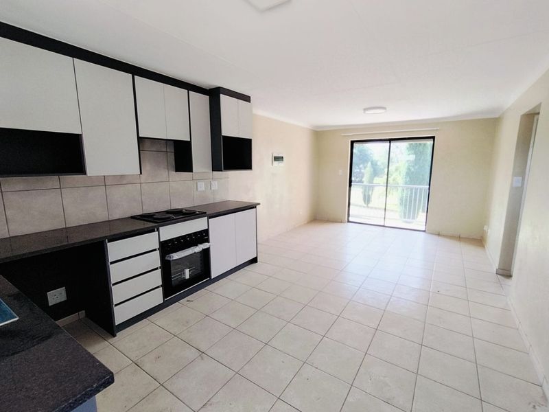 Open plan kitchen and living area featuring modern cabinetry, built-in oven and hob, tiled flooring, and sliding door access to the exterior.