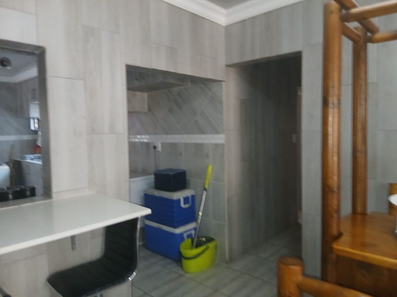 A functional scullery or utility area featuring tiled walls and flooring with a built-in counter space.