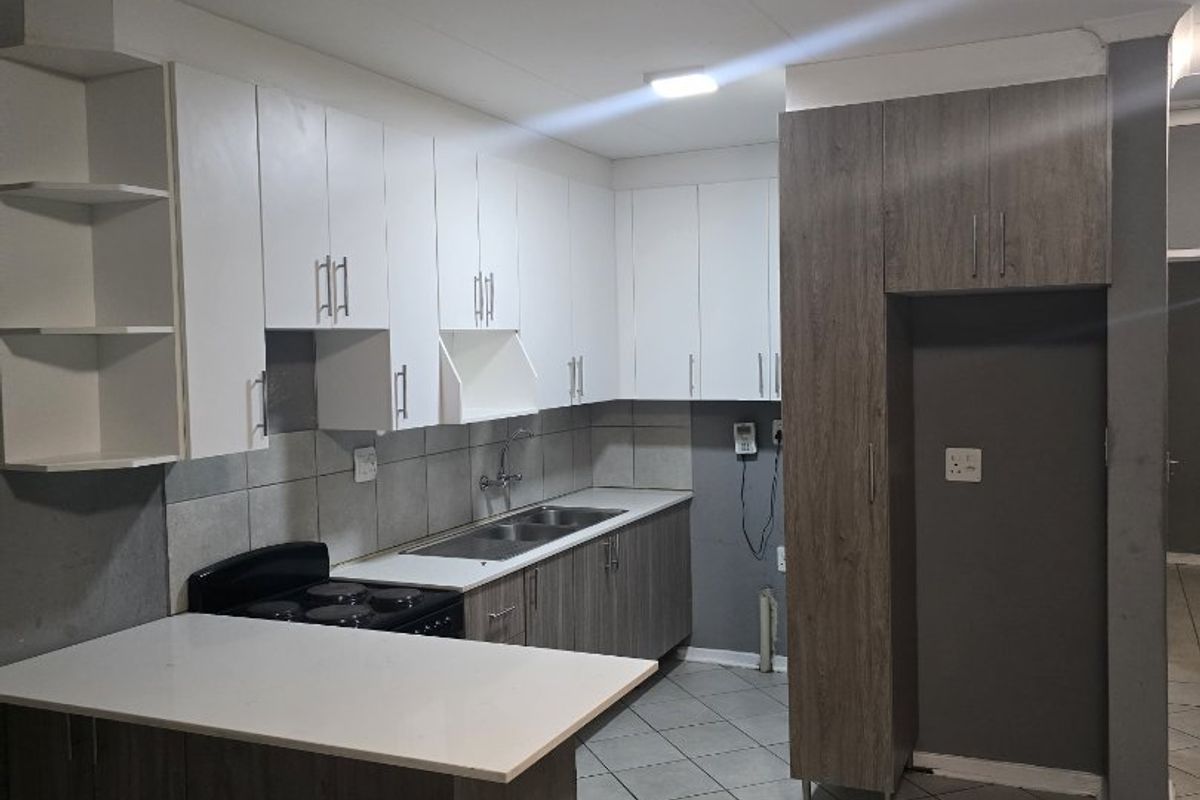 Modern kitchen featuring white and wood-grain cabinetry, stone-look countertops, tiled flooring, and a built-in electric stove with a breakfast nook.