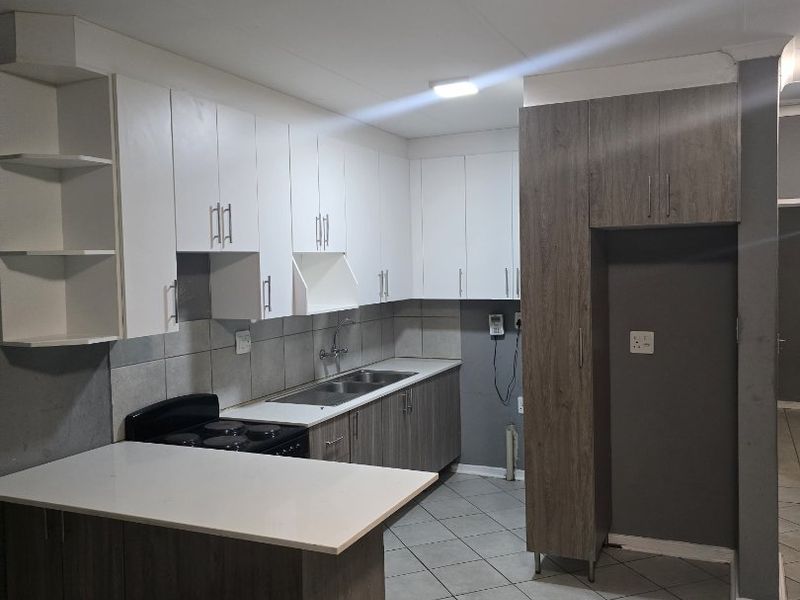 Modern kitchen featuring white and wood-grain cabinetry, stone-look countertops, tiled flooring, and a built-in electric stove with a breakfast nook.