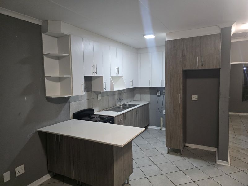 A functional kitchen featuring two-tone cabinetry, a double basin sink, electric stove, and a breakfast nook with tiled flooring throughout.
